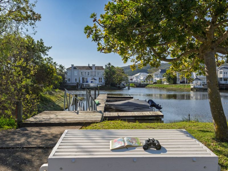 A scenic view of a tranquil canal with a private jetty and surrounding residential properties, showcasing peaceful waterfront living.