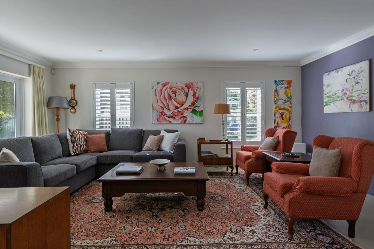 A well-maintained living room featuring plantation shutters, crown molding, and recessed lighting, creating a comfortable and inviting atmosphere.