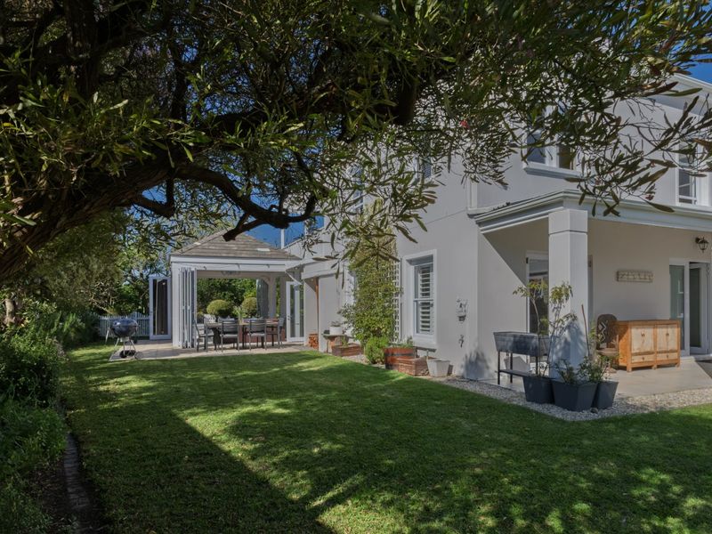 A well-maintained rear garden featuring a lush lawn, a covered patio area, and a detached gazebo, perfect for outdoor entertaining.