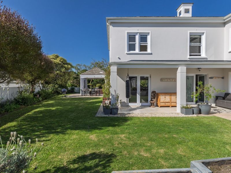 A well-maintained rear exterior featuring a covered patio, manicured lawn, and a detached gazebo, offering a pleasant outdoor living and entertainment space.