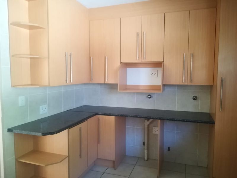 A functional kitchen featuring light wood-finish cabinetry, dark granite countertops, and a tiled backsplash, offering a clean and neutral space for culinary activities.