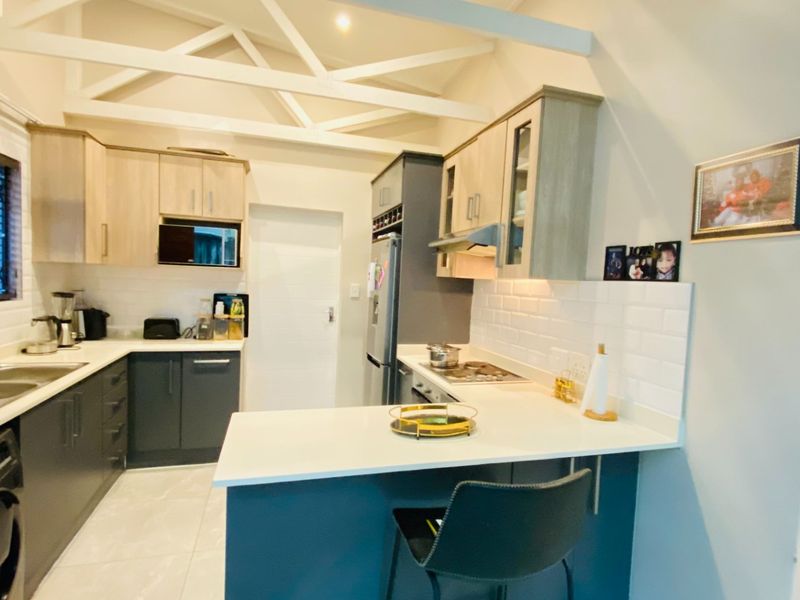 Modern kitchen featuring subway tile backsplash, quartz countertops, built-in cabinetry, and exposed roof trusses, creating a bright and functional culinary space.