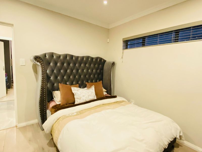 A well-maintained bedroom featuring neutral walls, recessed downlighting, and a high-set horizontal window with fitted venetian blinds.
