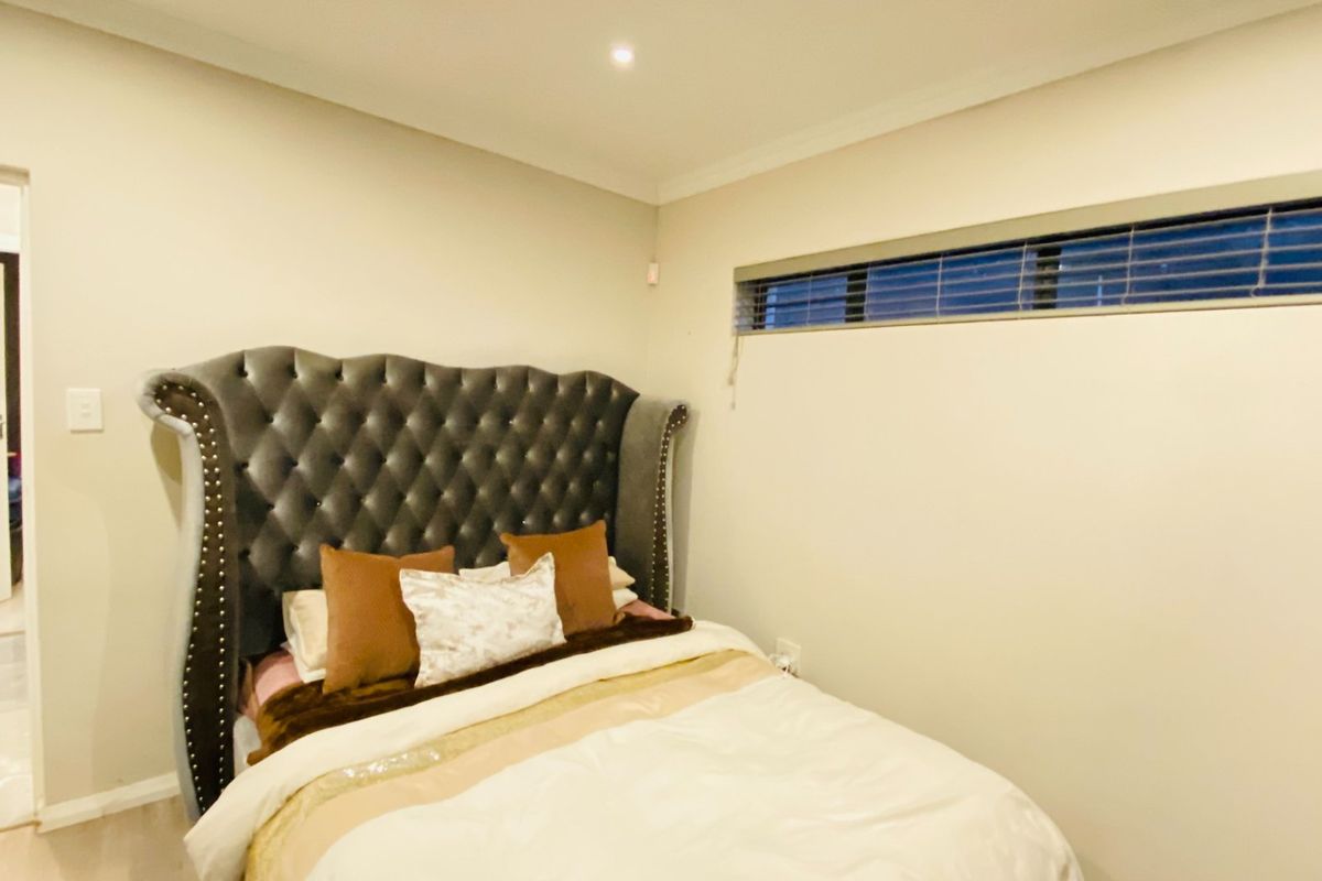 A well-maintained bedroom featuring neutral walls, recessed downlighting, and a horizontal window with fitted blinds.