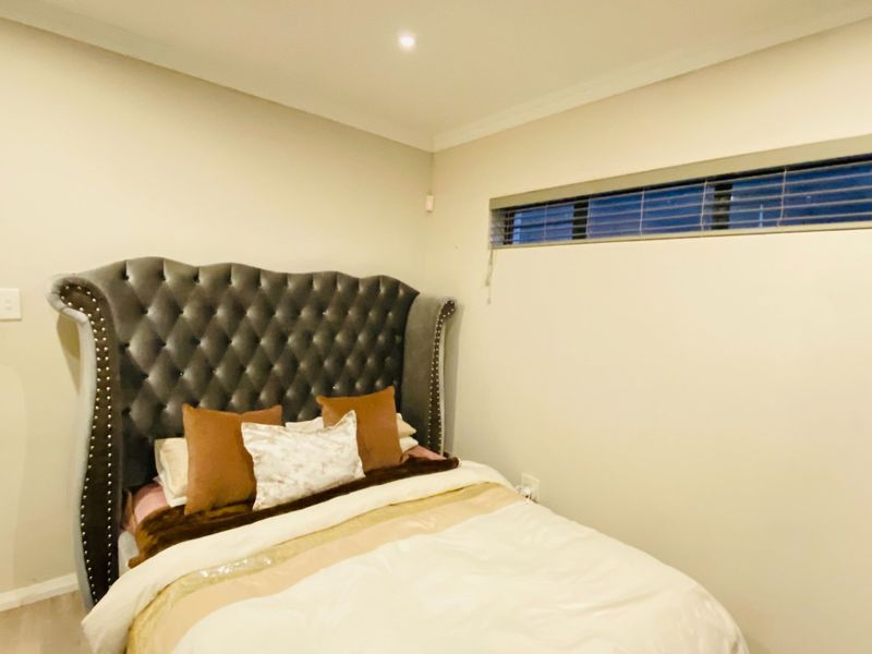 A well-maintained bedroom featuring neutral walls, recessed downlighting, and a horizontal window with fitted blinds.