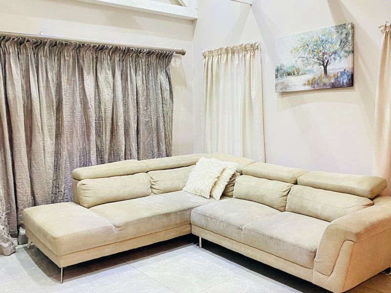 A bright living room featuring neutral tiled flooring and a high vaulted ceiling, creating an open and airy atmosphere.
