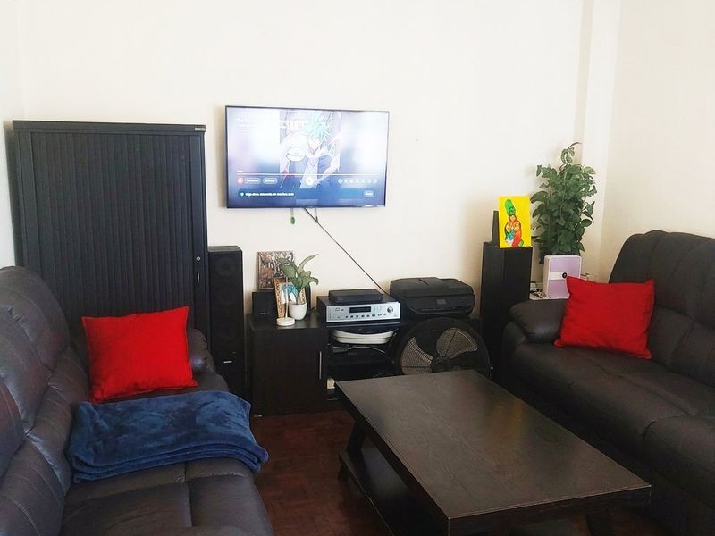 A living room featuring dark parquet flooring and neutral wall finishes, providing a functional space for relaxation and entertainment.