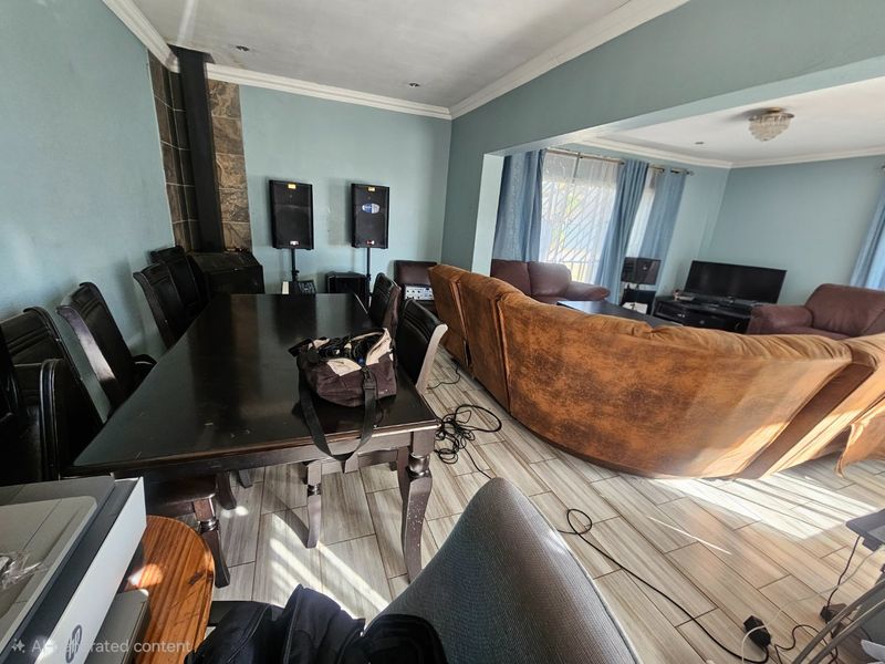 Open-plan living and dining area featuring tiled flooring, coved cornicing, and a built-in wood-burning fireplace.