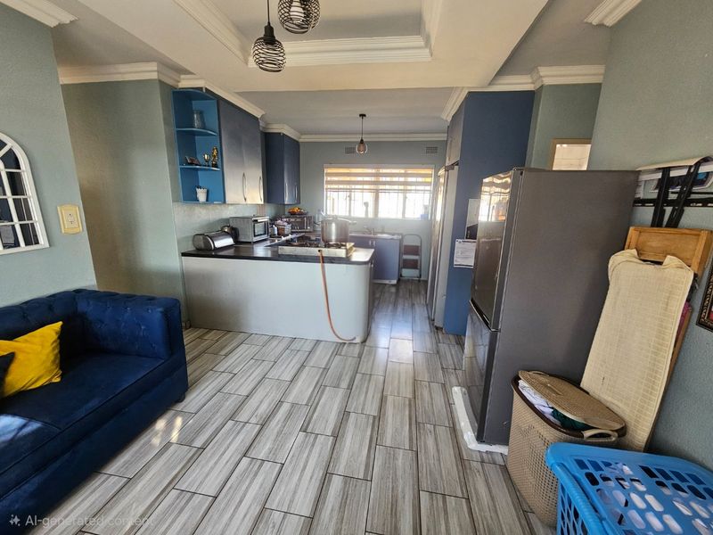 Open-plan kitchen and living area featuring blue cabinetry, wood-look tile flooring, and a central kitchen island with integrated sink and cooktop.