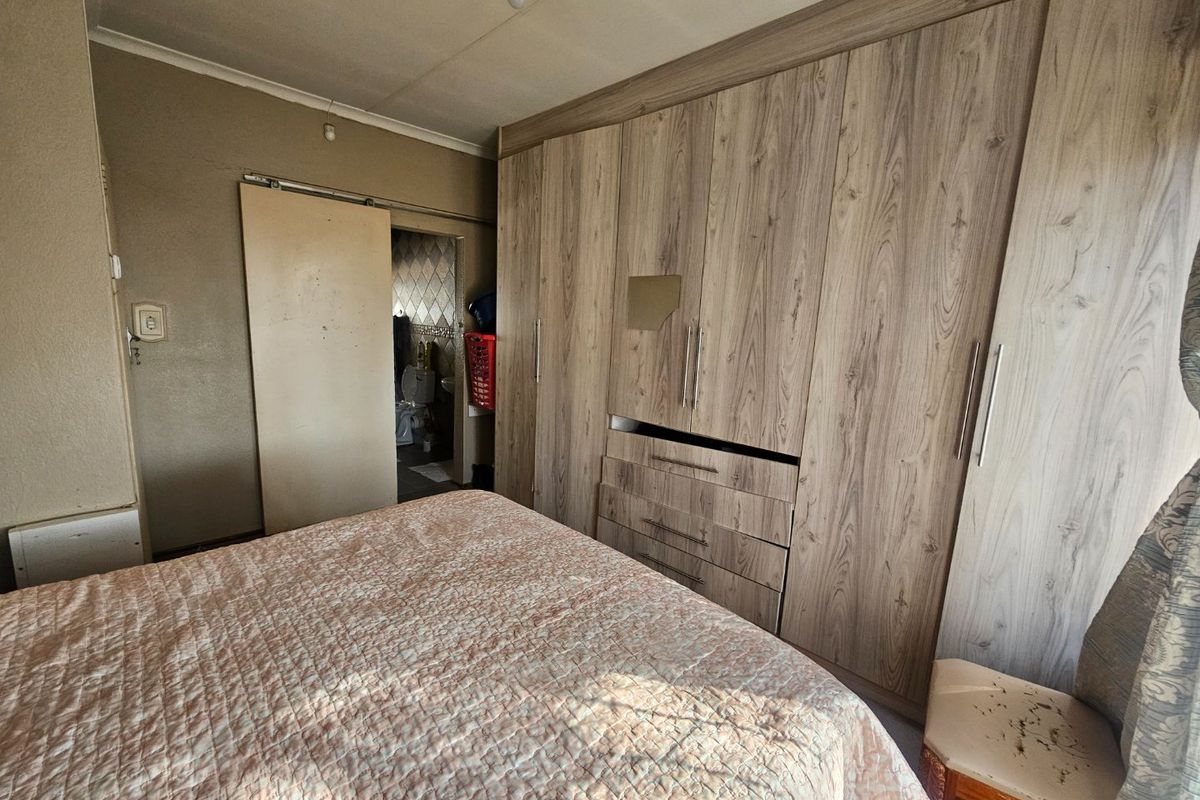 A bedroom featuring extensive built-in wooden cupboards and a sliding door leading to an adjacent bathroom area.
