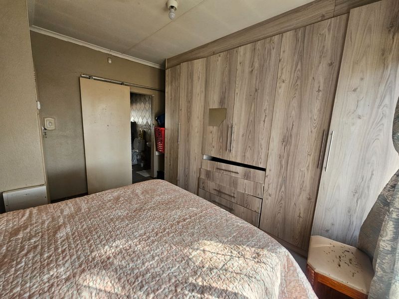 A bedroom featuring extensive built-in wooden cupboards and a sliding door leading to an adjacent bathroom area.