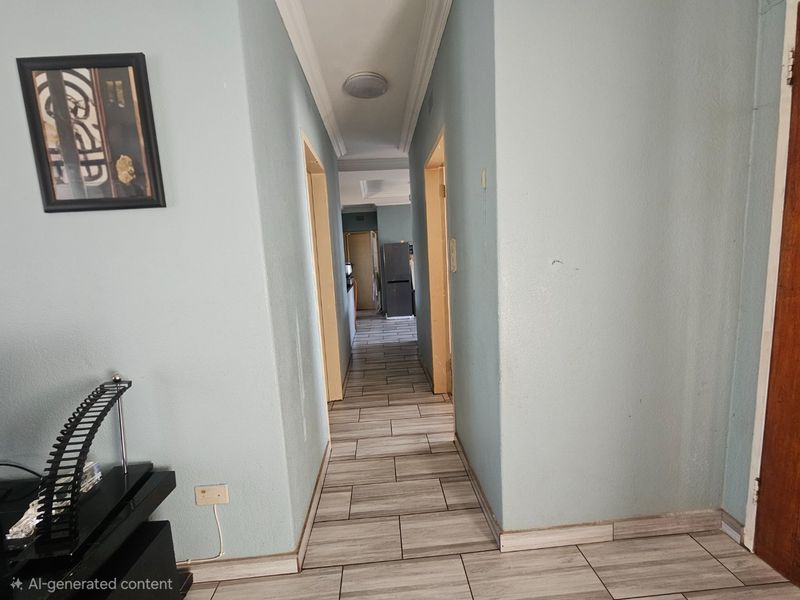 A functional hallway featuring light-colored tiled flooring, crown molding, and neutral wall finishes, providing access to adjacent rooms within the home.