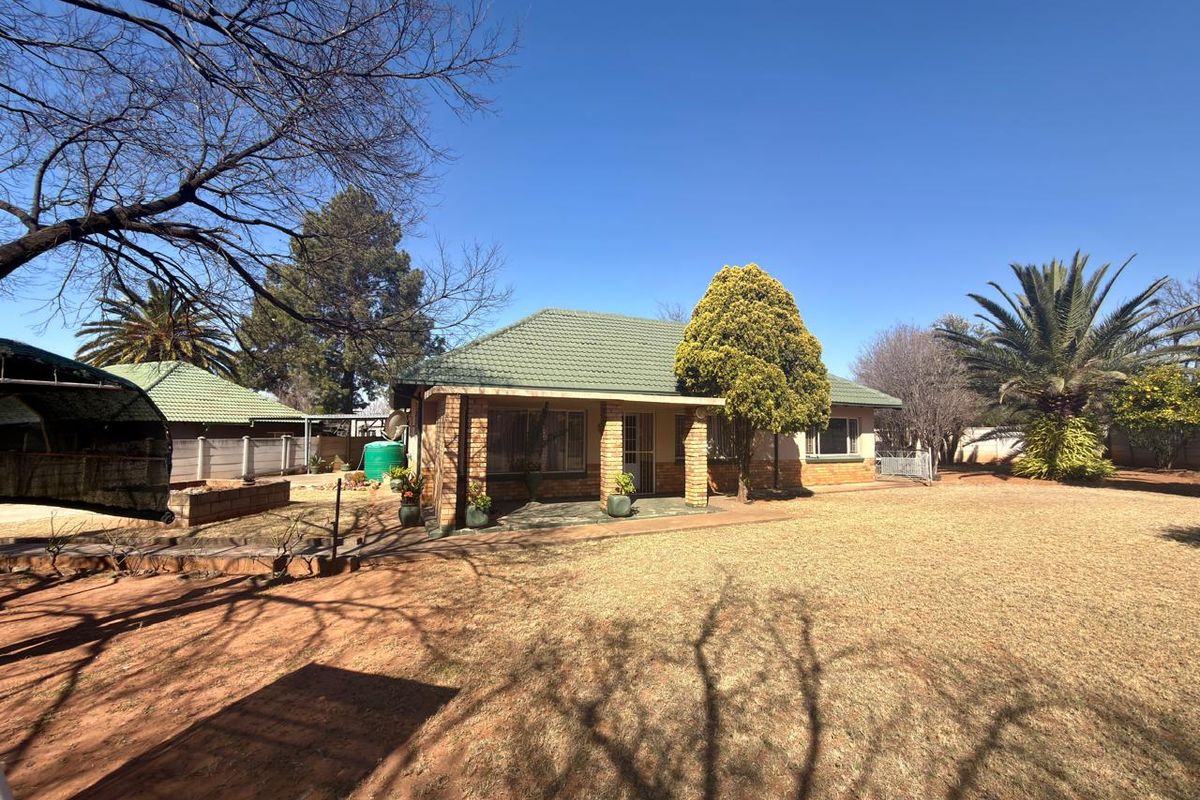 A view of the rear exterior of the house featuring a tiled roof, brick facade, and a covered patio area overlooking the garden.