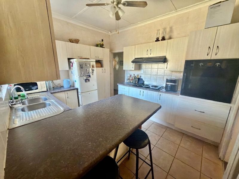 Functional kitchen featuring built-in cabinetry, laminate countertops, integrated oven, hob, and extractor fan with tiled flooring.