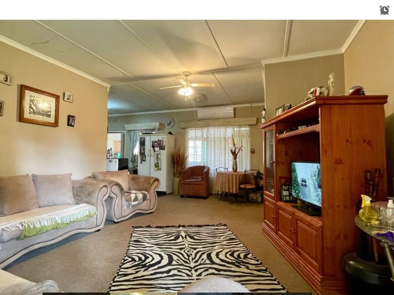 Spacious living area featuring a ceiling fan, split-system air conditioning, and tiled ceiling panels, offering a functional layout for relaxation.
