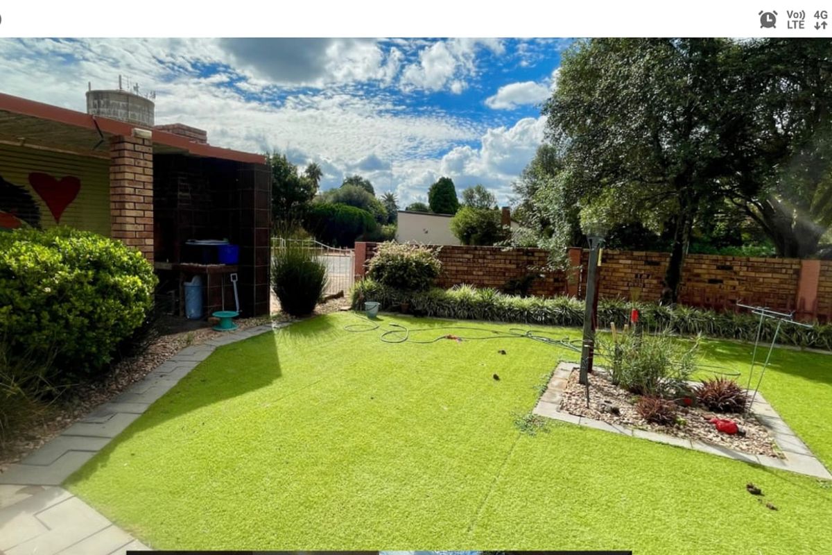 A rear garden area featuring a built-in brick braai, paved pathways, and a lawn enclosed by a brick boundary wall.