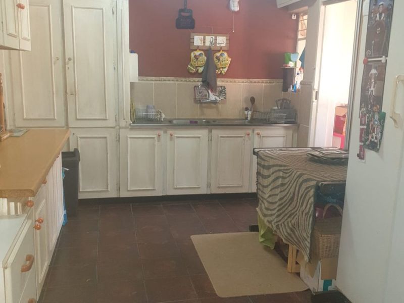 A functional kitchen featuring built-in cabinetry, laminate countertops, and a stainless steel sink, with ceramic floor tiles and an integrated air conditioning unit.