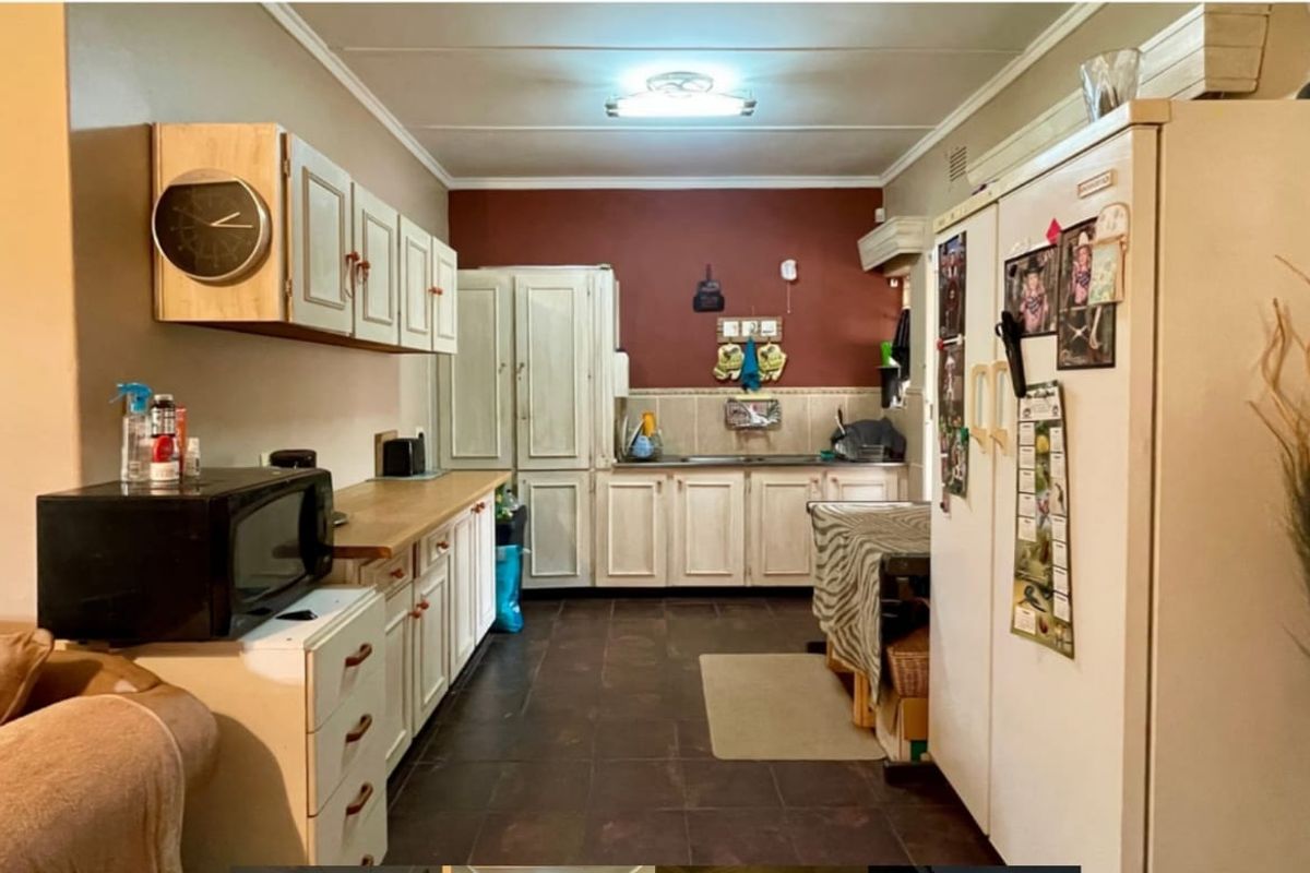 A functional kitchen featuring dated cabinetry, laminate countertops, tiled backsplash, and tiled flooring, offering potential for a modern renovation.