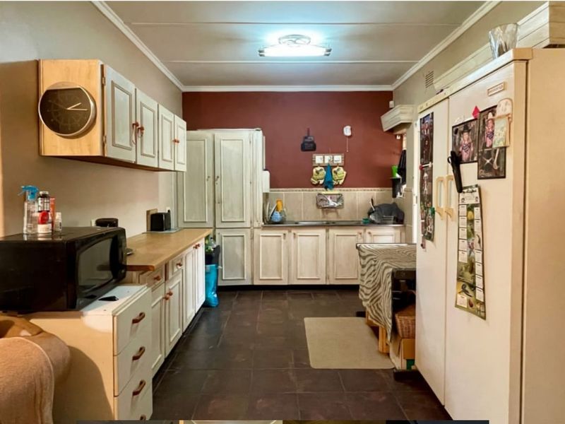 A functional kitchen featuring dated cabinetry, laminate countertops, tiled backsplash, and tiled flooring, offering potential for a modern renovation.