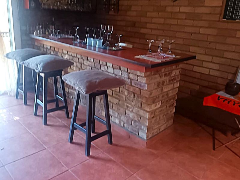 A rustic indoor bar area featuring a built-in brick counter, exposed brick walls, and tiled flooring.