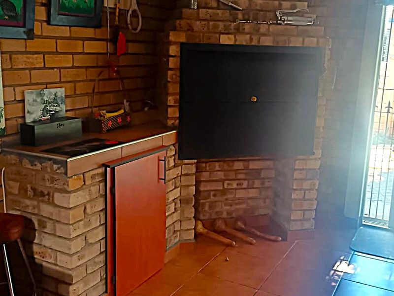 Covered patio area featuring a built-in brick braai, tiled flooring, and a small prep counter, providing a functional space for outdoor entertaining.
