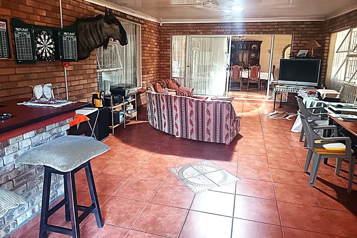 Spacious living area featuring exposed brick walls, tiled flooring, and a built-in brick bar, with sliding doors leading to an adjacent dining space.