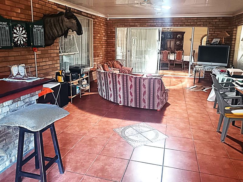 Spacious living area featuring exposed brick walls, tiled flooring, and a built-in brick bar, with sliding doors leading to an adjacent dining space.