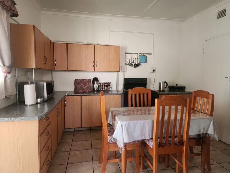 A functional kitchen featuring laminate cabinetry, stone-look countertops, tiled flooring, and a dedicated dining area with a freestanding stove.
