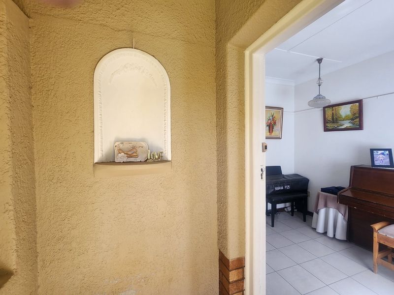 Entrance area featuring a decorative arched wall niche, leading into a tiled living space with coved ceilings and pendant lighting.