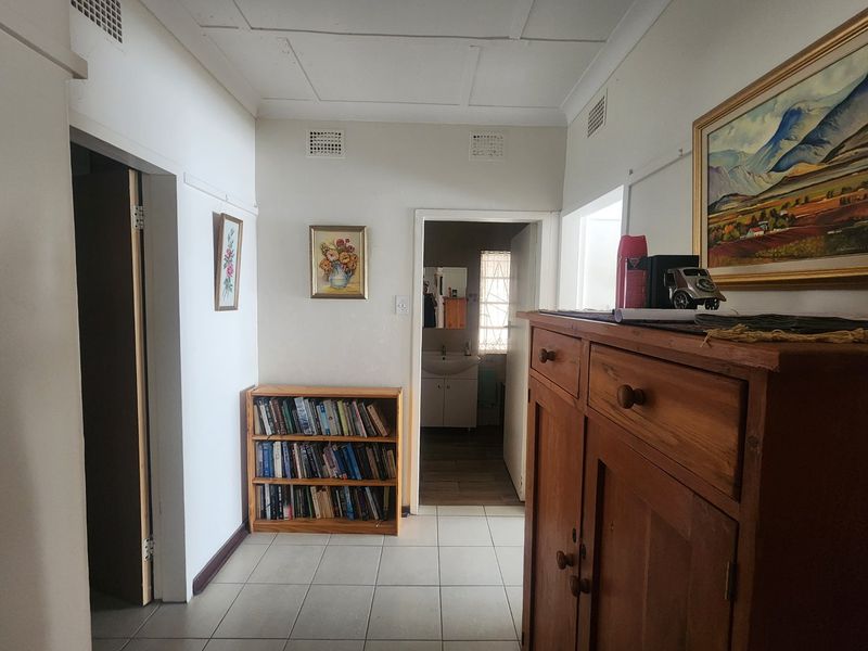 A functional hallway featuring tiled flooring and access to adjacent rooms, showing signs of age in the ceiling and finishes.