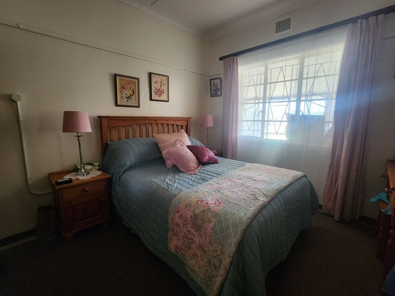 A cozy bedroom featuring a window with security bars, classic picture rails, and coving detail, offering a comfortable and functional living space.