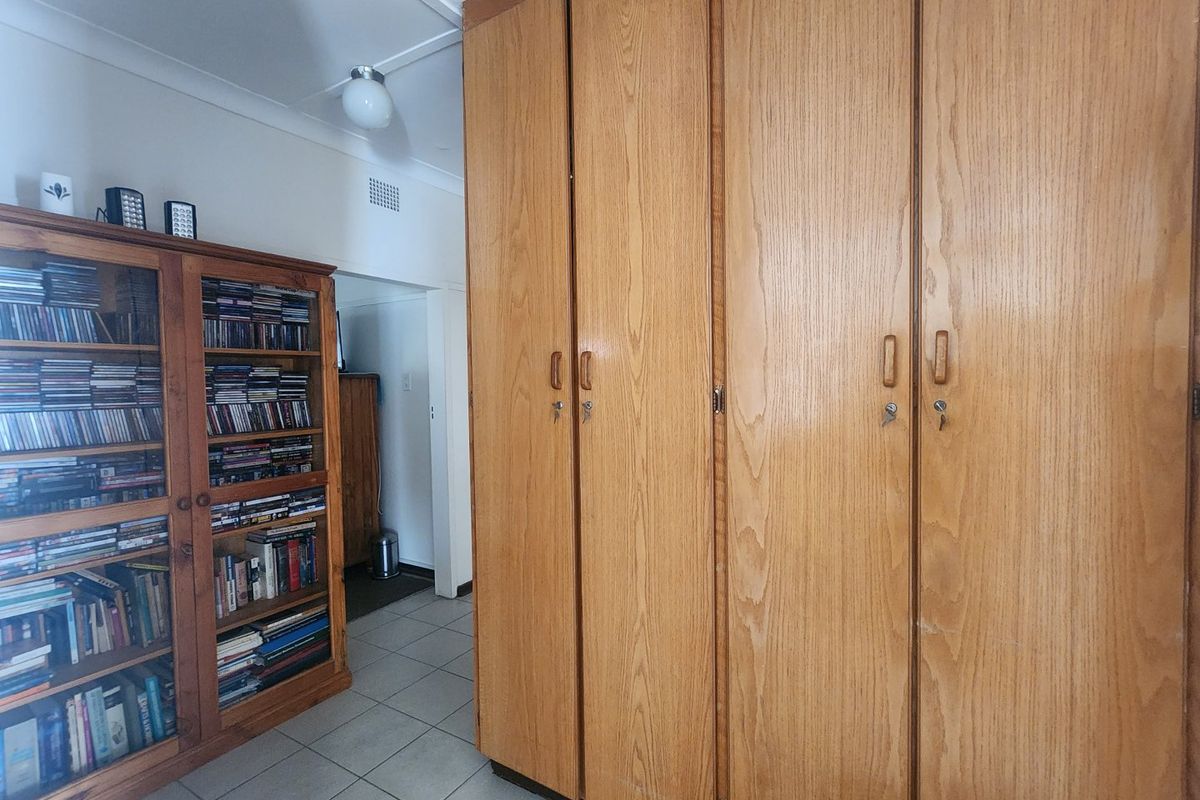A bedroom featuring floor-to-ceiling built-in wooden cupboards and tiled flooring, offering practical storage space.