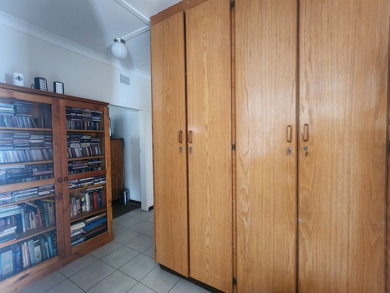 A bedroom featuring floor-to-ceiling built-in wooden cupboards and tiled flooring, offering practical storage space.