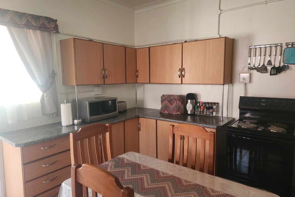 A functional kitchen featuring laminate cabinetry, stone-look countertops, and a built-in electric stove, offering a practical layout with potential for modern cosmetic updates.