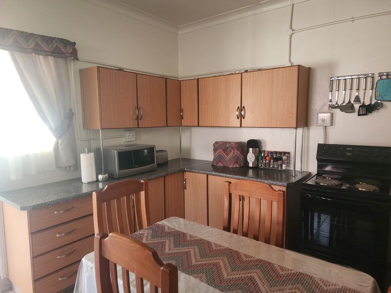 A functional kitchen featuring laminate cabinetry, stone-look countertops, and a built-in electric stove, offering a practical layout with potential for modern cosmetic updates.