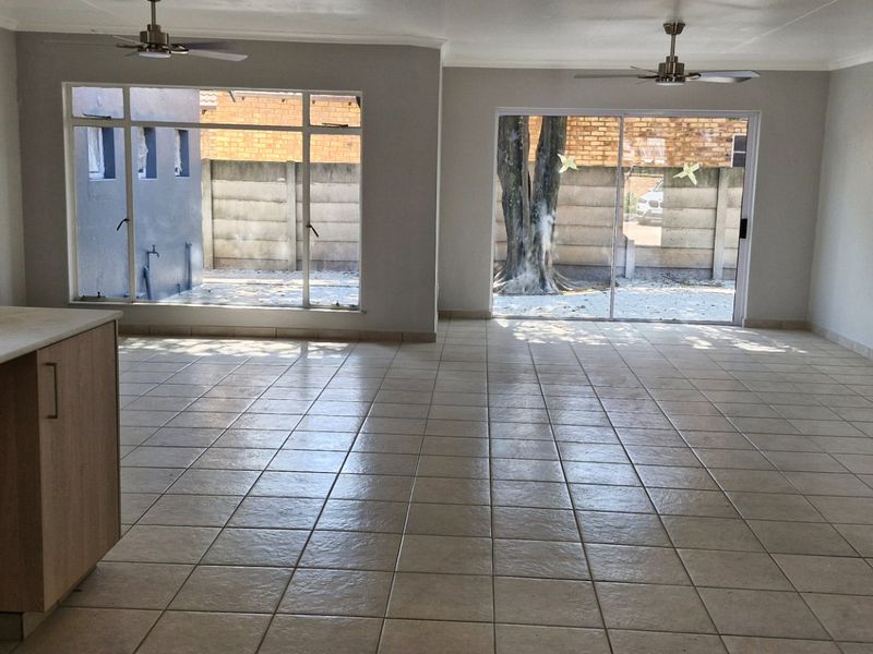 Spacious open-plan living area featuring tiled flooring, ceiling fans, and direct access to the rear exterior through sliding glass doors.