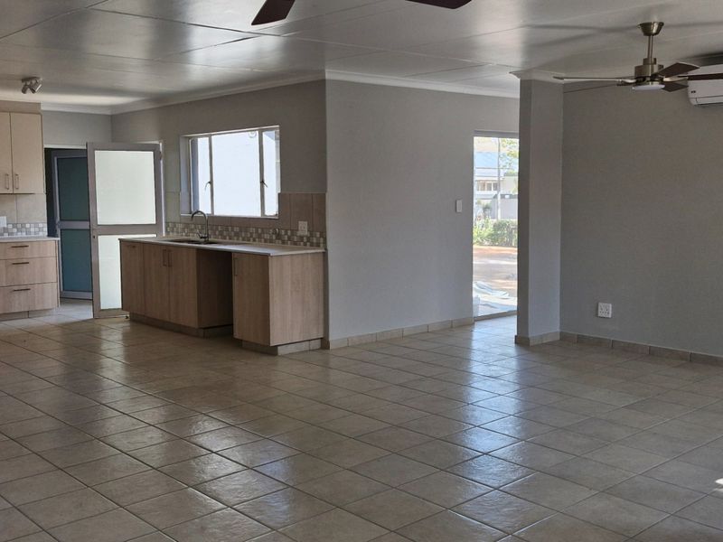 Spacious open-plan living area featuring tiled floors, a modern kitchen with built-in cabinetry, and a split-system air conditioner.