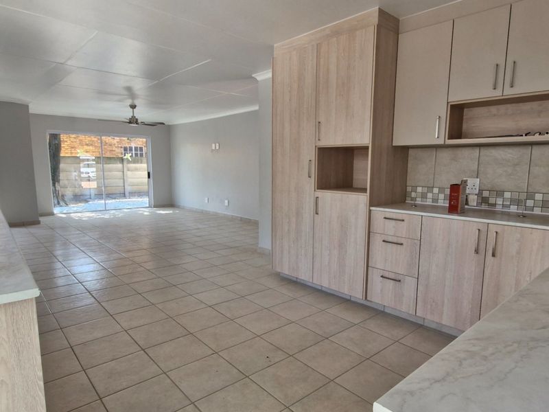 Spacious open-plan kitchen and living area featuring light wood cabinetry, gas hob, tiled flooring, and sliding doors leading to the exterior.