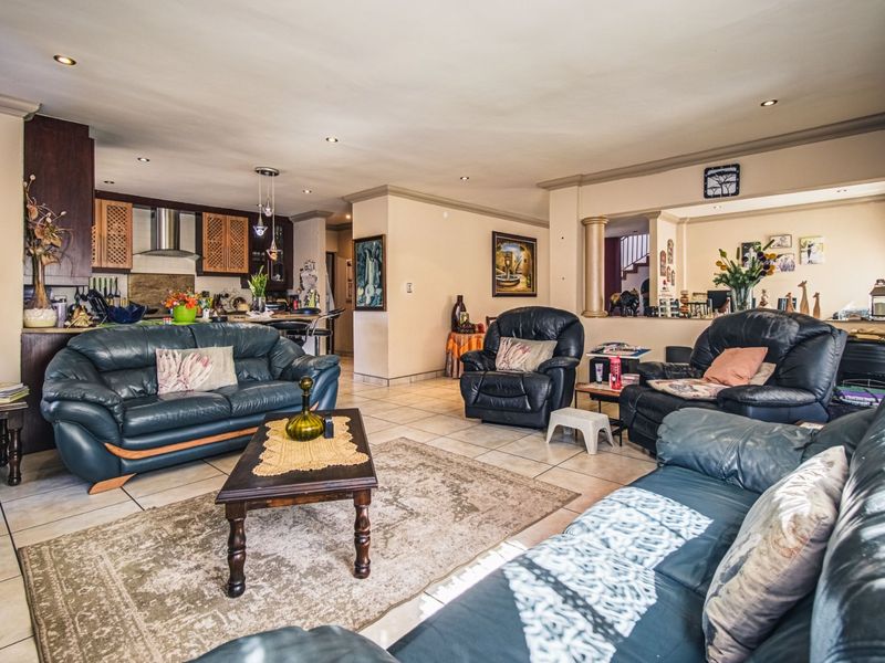 Spacious open-plan living area featuring tiled floors, recessed lighting, and an integrated kitchen with dark wood cabinetry and a breakfast counter.