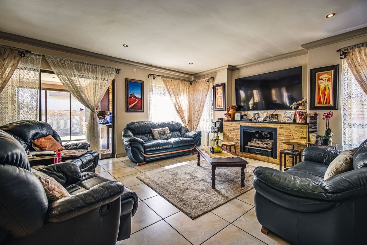 Spacious living room featuring tiled flooring, a stone-clad fireplace, and sliding glass doors leading to an outdoor area.