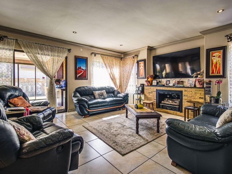 Spacious living room featuring tiled flooring, a stone-clad fireplace, and sliding glass doors leading to an outdoor area.