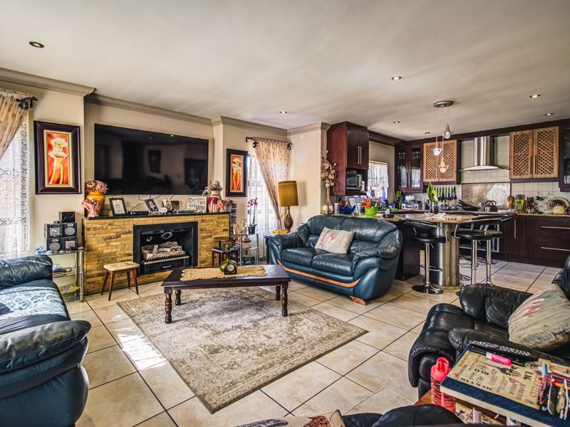 Spacious open-plan living area featuring a stone-clad fireplace and a modern kitchen with built-in cabinetry, island, and stainless steel extractor fan.