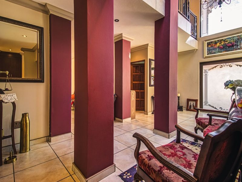 Spacious entrance foyer featuring tiled flooring, prominent structural columns, and a double-height ceiling area with natural light.