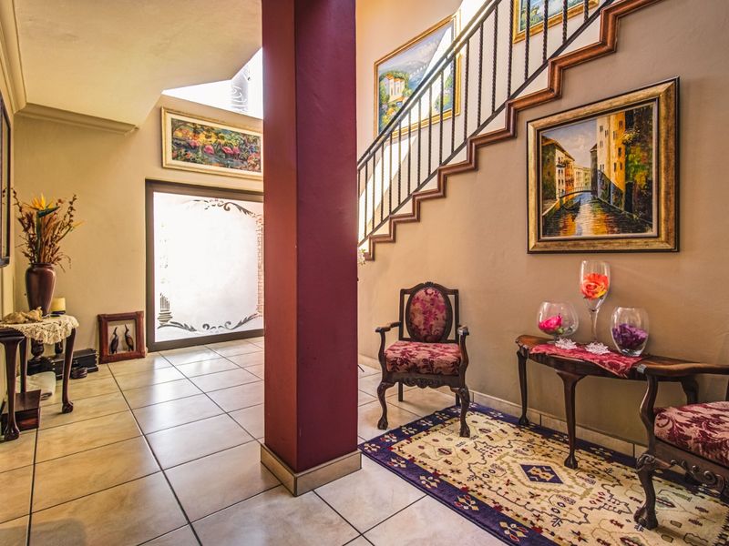 Spacious entrance hall featuring tiled flooring, a prominent structural column, and a staircase with a decorative wrought iron balustrade.