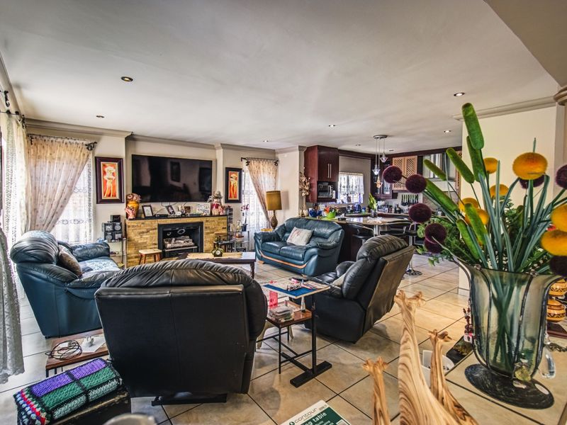 Spacious open-plan living area featuring a stone-clad fireplace and a connected kitchen with built-in cabinetry and a central island.