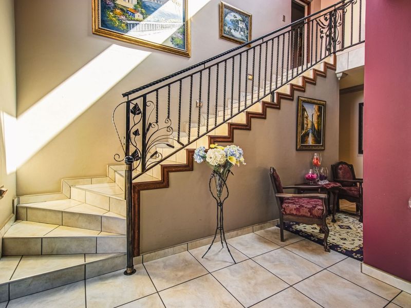 Welcoming entrance hall featuring a tiled staircase with decorative wrought iron balustrades and neutral ceramic floor tiling.