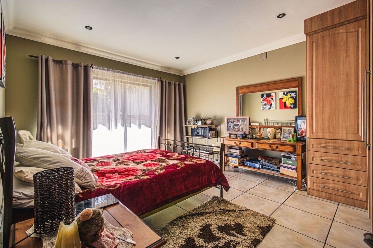 Spacious bedroom featuring tiled flooring, recessed downlights, and a large built-in wardrobe with direct access to the exterior via sliding glass doors.
