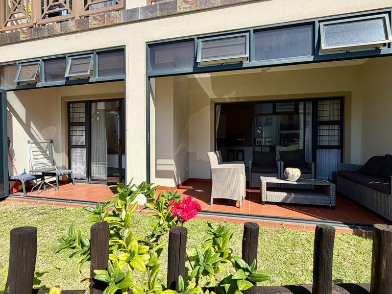 A covered ground-floor patio with tiled flooring and large sliding glass doors providing seamless access to the interior living space.