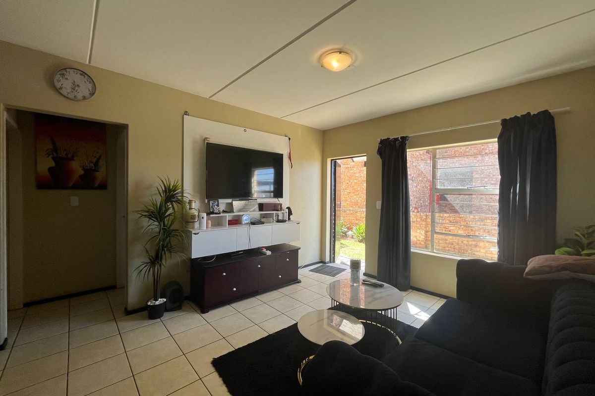 A living room featuring tiled flooring, aluminium window frames, and direct access to an outdoor area.