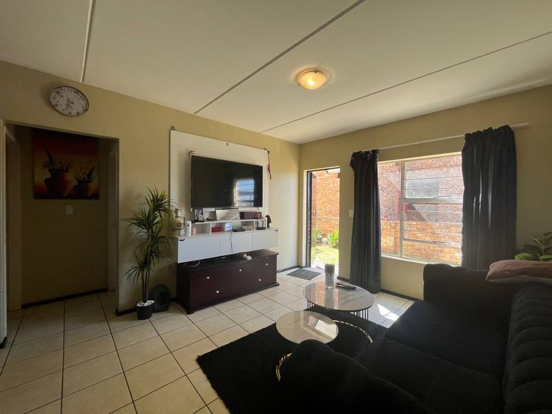 A living room featuring tiled flooring, aluminium window frames, and direct access to an outdoor area.